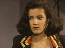 a woman is wearing a black jacket with gold trim and a red collar