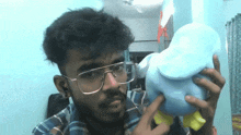 a man wearing glasses is holding a stuffed elephant
