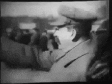 a black and white photo of a man in a military uniform talking into a microphone .