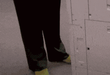 a person wearing black pants and yellow socks is standing in front of white lockers