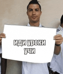 a man in a white shirt is holding a white sign with russian writing .