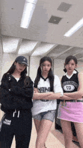 three girls are posing for a picture in a room with their arms crossed