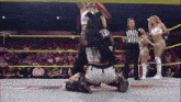 a female wrestler is kneeling down in a wrestling ring while a referee looks on