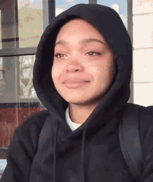 a woman wearing a black hoodie is crying and looking at the camera .