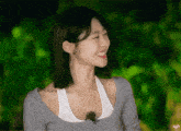 a woman wearing a grey tank top and a white tank top is smiling .