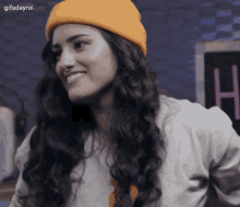 a woman wearing a yellow beanie is smiling with the gifsdayrol logo behind her