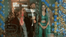 a group of people are standing in front of balloons and a telly masala sign