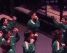 a group of people are standing in a room with their hands up in the air .