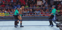 a referee is standing in the middle of a wrestling ring with a wrestler in the background .