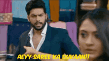 a man in a suit is pointing at a woman and says aeyy saree ka dukaan !