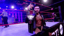 a man is holding a wrestling championship belt in a wrestling ring .