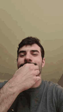 a man with a beard and mustache covering his mouth with his hand