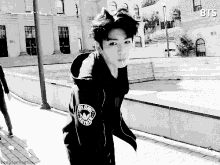 a black and white photo of a young man wearing a hoodie with the word bts on it .