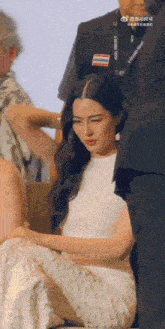 a woman in a white dress is sitting next to a man in a black suit
