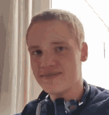 a young man wearing headphones and a blue shirt is smiling .