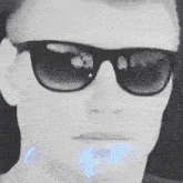 a close up of a person wearing sunglasses with a blue light coming out of his mouth