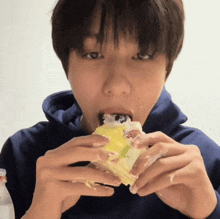 a person in a blue hoodie is eating a cake