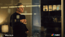 a man standing in front of a window with #suitsla on the bottom right