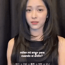 a woman with long black hair is wearing a black dress and talking to someone in another language .