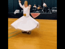 a man in a white skirt is dancing on a wooden floor .