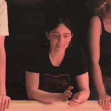 a woman wearing a t-shirt that says ' rolling stones ' on it sits at a table