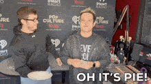 two men are standing in front of a wall that says iheart radio