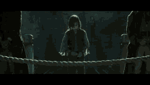 a young girl is standing in a dark room with a man in the background