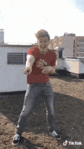 a man in a red tommy hilfiger shirt is dancing on a roof