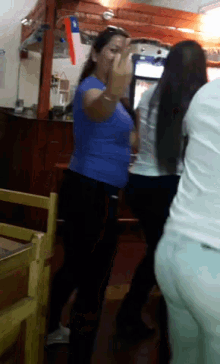 a woman in a blue shirt is standing in front of a fridge