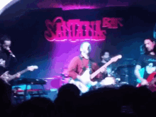 a man playing a guitar in front of a sign that says sinner