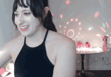 a woman in a black tank top is smiling in front of a table