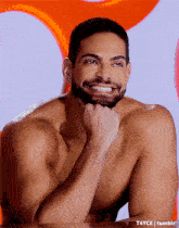 a shirtless man with a beard is smiling with his hand on his chin ..