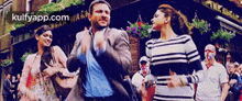 a man and a woman are dancing on a street in front of a building .