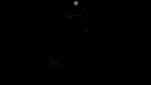 a black and white photo of a person sitting in the dark with their hands crossed .