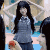 a girl in a school uniform is standing in front of a group of people