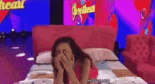 a woman is laying on a bed covering her face