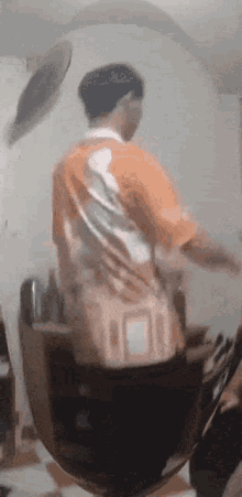 a man in an orange shirt is standing in front of a mirror ..