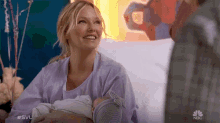 a woman in a hospital gown is holding a baby with the nbc logo in the corner