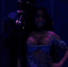 a woman in a blue top is smiling in front of a microphone while a man stands behind her