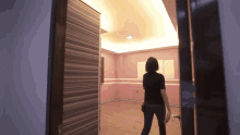 a woman standing in an empty room with a pink wall