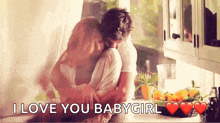 a man and a woman are hugging in a kitchen and the man is saying `` i love you babygirl '' .