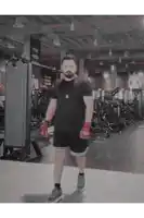 a man wearing boxing gloves in a gym with a sign behind him that says t2ui