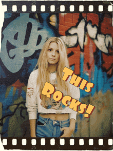 a woman is standing in front of a graffiti wall with the words this rocks