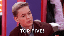 a young man in a brown jacket says " top five "