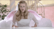 a woman in a white dress and pink wings is sitting on a table .
