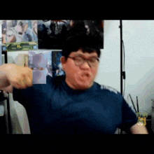 a man wearing glasses and a blue shirt is pointing at something