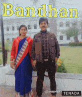 a man and a woman are posing for a photo in front of a building that says bandhan on it