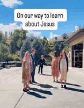 a family is walking down a sidewalk in front of a house with the words `` on our way to learn about jesus '' above them .