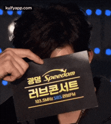 a man is covering his face with a sign that says speedom