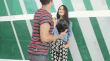 a man and woman are standing next to each other in front of a green and white striped wall .